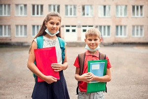 dzieci w maseczkach przed szkola