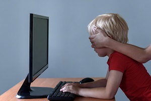 chlopiec przy laptopie zakryte oczy
