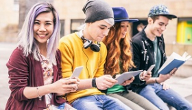 usmiechnieci nastolatkowie z tabletami i smartfonami